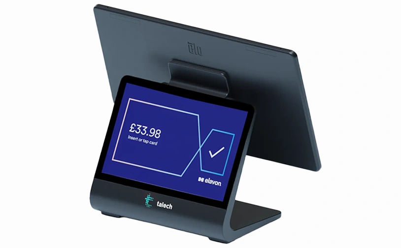 Customer making a contactless card payment at a clothing store checkout counter with shopping bag and garments in the background.