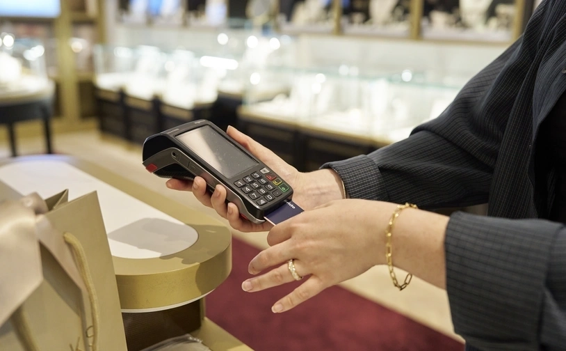 Card being inserted into a payment terminal by a worker at a jewellery store checkout counter