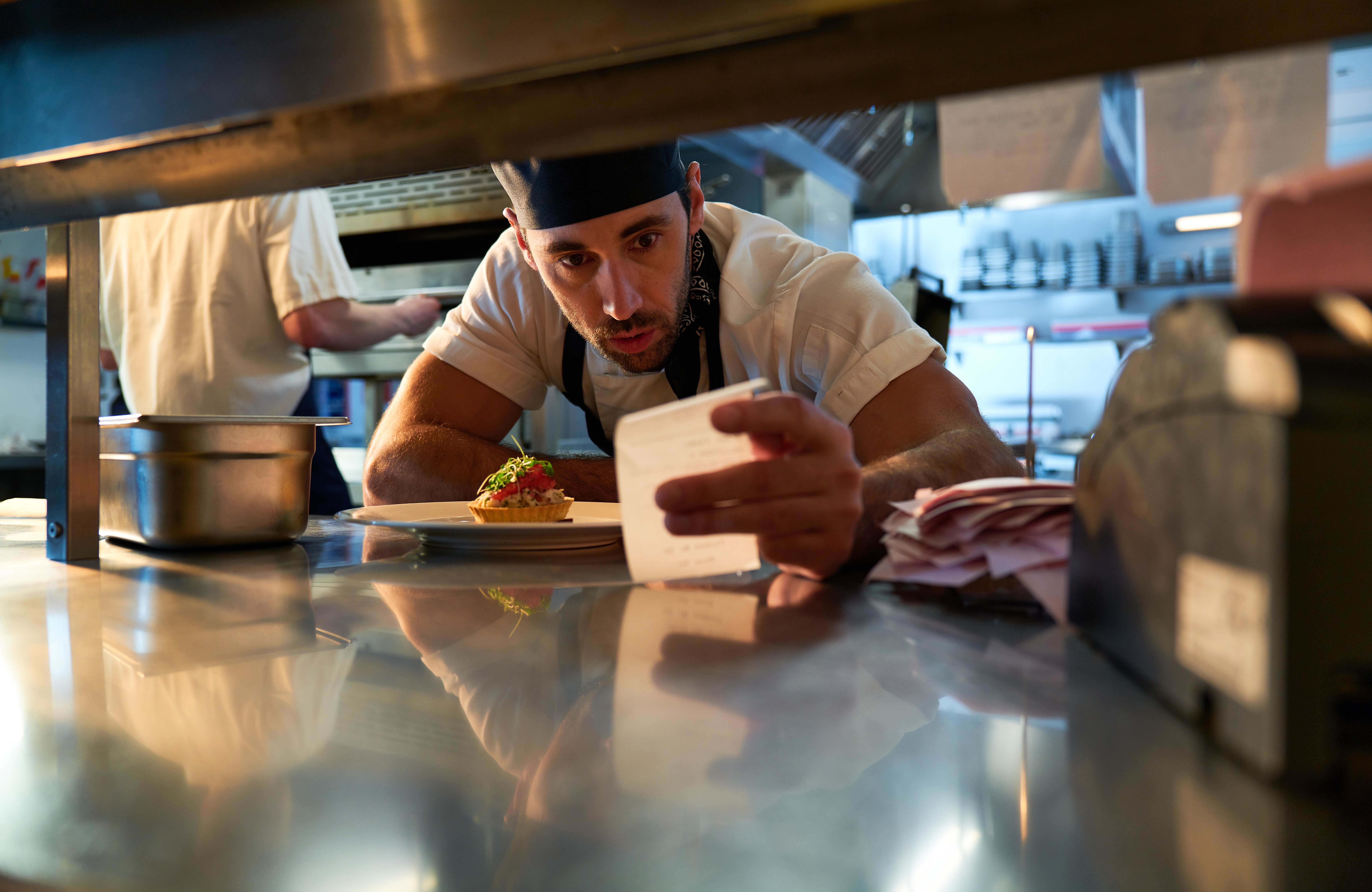 Restaurant staff taking an order using a digital tablet at a professional kitchen pass